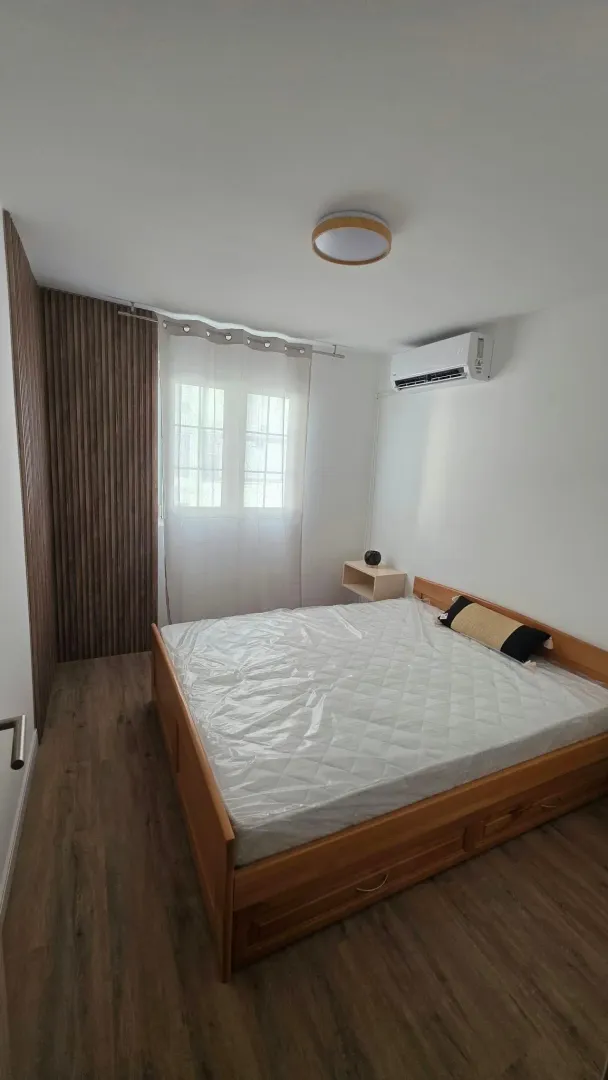 Modern bedroom with a double bed, wooden flooring, and decorative wall panels.