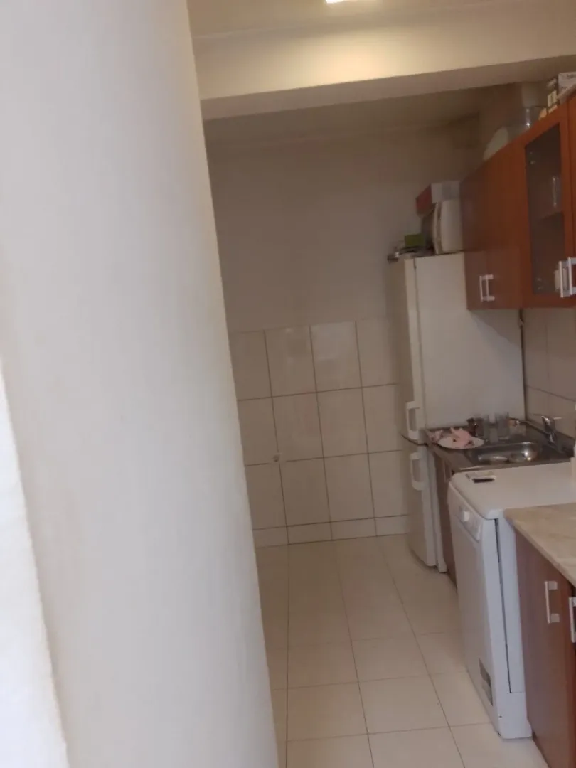 Mala kuhinja sa kuhinjskim elementima i frižiderom.