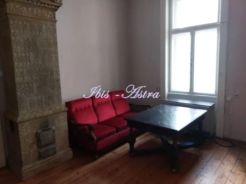 Living room with a red sofa, wooden table, and traditional stove.