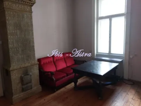Living room with a red sofa, wooden table, and traditional stove. - image 11