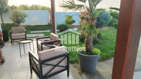 Natkrivena terasa sa garniturom za sedenje i pogledom na uređeno dvorište sa palmom. - image 3