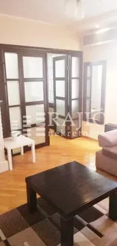 Living room with a sofa, coffee table, and wooden partition doors. - image 7