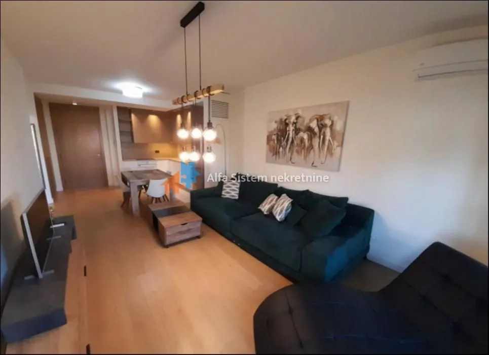 Living room with sofa, dining area, and kitchen in the background.