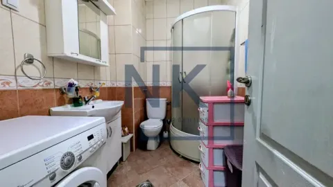 Bathroom with a shower cabin, washbasin, toilet, and washing machine. - image 18