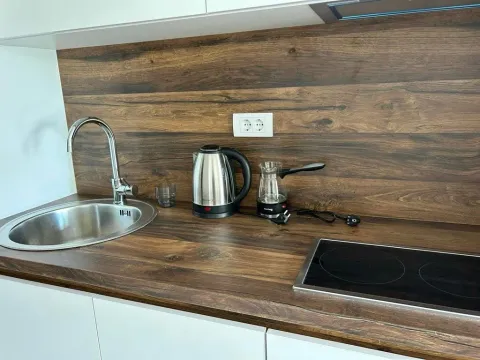 Dio kuhinje sa sudoperom, radnom pločom u dezenu drveta i ugradnom pločom. - image 4