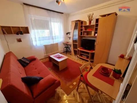 Manji dnevni boravak sa crvenim kaučem, drvenim nameštajem, radnim stolom i trpezarijskim stolom. - image 2