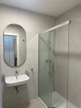Modern bathroom with a sink, mirror, and shower enclosure. - image 4