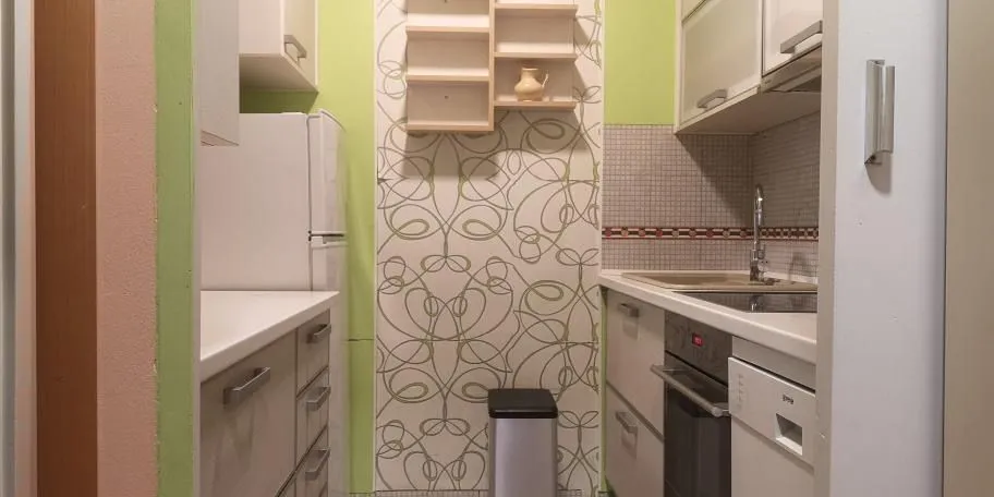 Mala, funkcionalna kuhinja sa svijetlim elementima i zelenim detaljima.