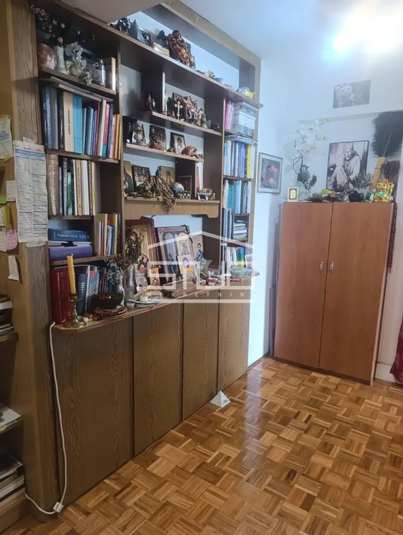 Living room with a large wooden shelving unit and parquet flooring.