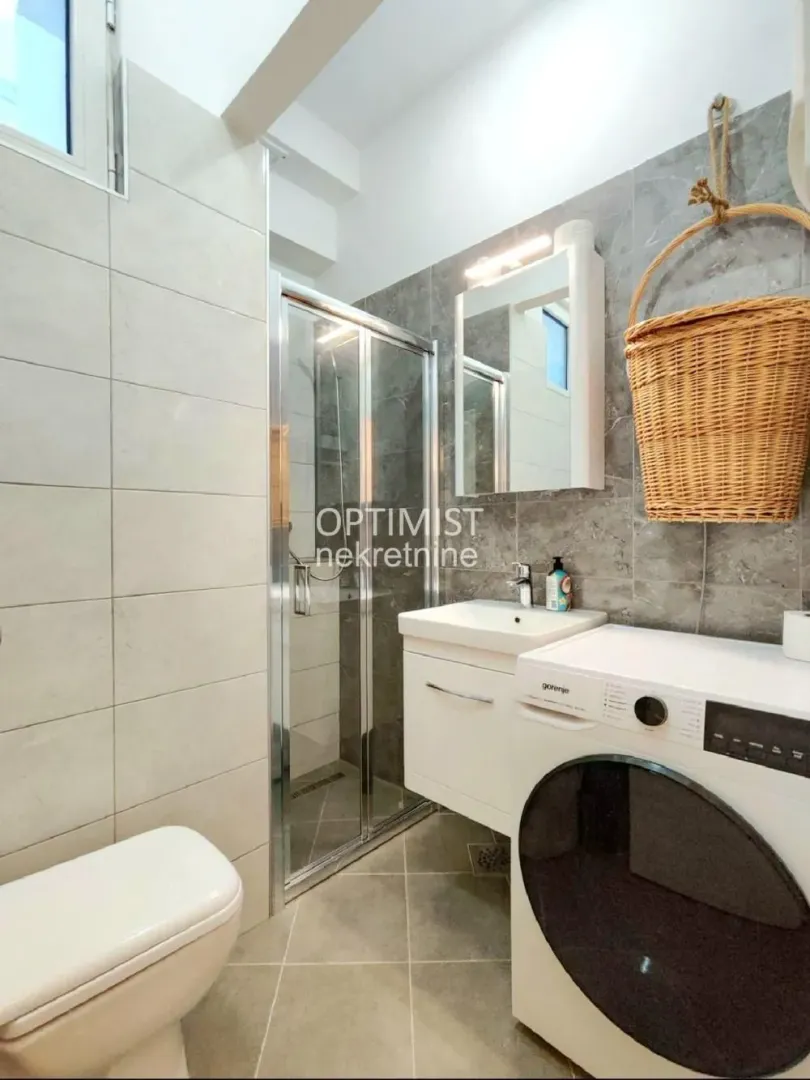 Bathroom with a shower cabin, washbasin, and washing machine.