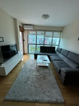 Namještena dnevna soba sa ugaonom garniturom, televizorom i velikim prozorom. - image 2