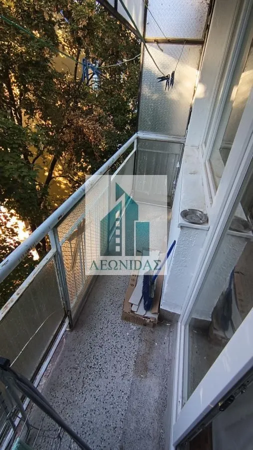 Small enclosed balcony with a railing and a view of greenery.
