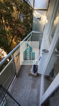 Small enclosed balcony with a railing and a view of greenery. - image 3