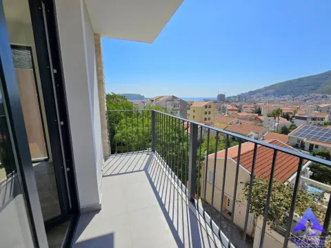 Nenamješten balkon sa metalnom ogradom i pogledom na grad i more. - image 7