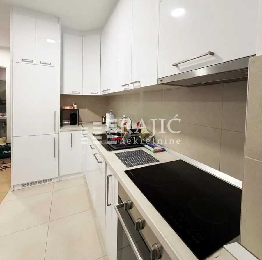 Modern white kitchen with built-in hob and cabinetry.