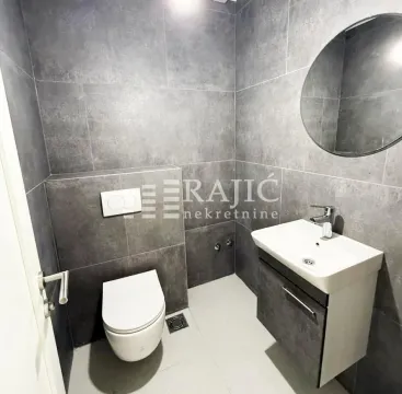 Moderno opremljeno kupatilo sa sivim zidnim pločicama, umivaonikom i toaletom. - image 12