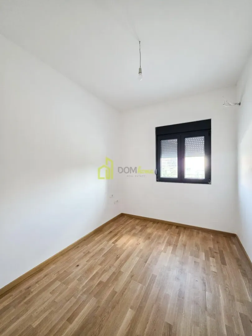 Empty room with white walls, wooden flooring and a window.