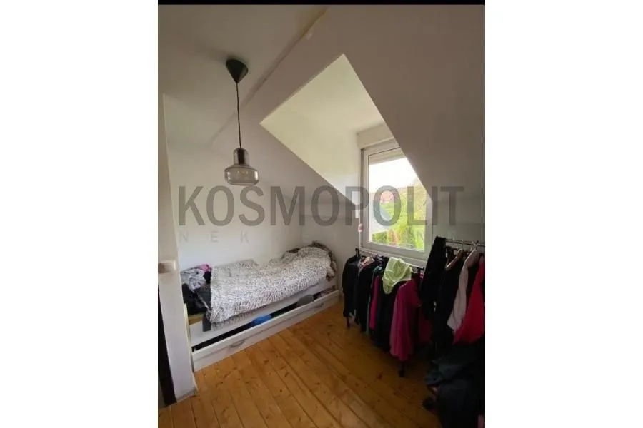 Manja spavaća soba sa krevetom i drvenim podom.