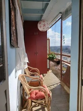 Covered balcony with wicker furniture, a built-in wardrobe, and a view of the surroundings. - image 3