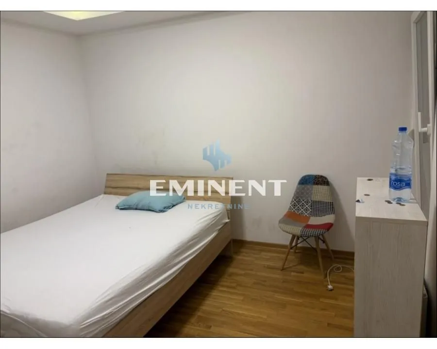 Small bedroom with a double bed, a desk, and a patterned chair.