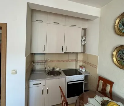 A small kitchen with light cabinets, a stove, and a sink. - image 4