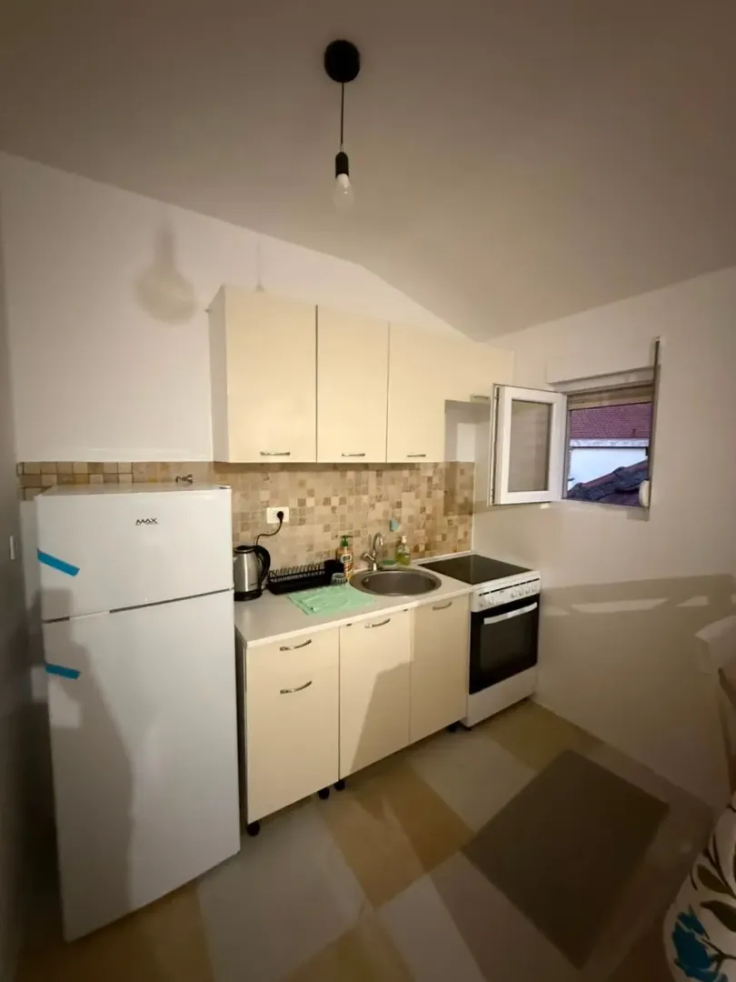 Small equipped kitchen with white goods and a window.
