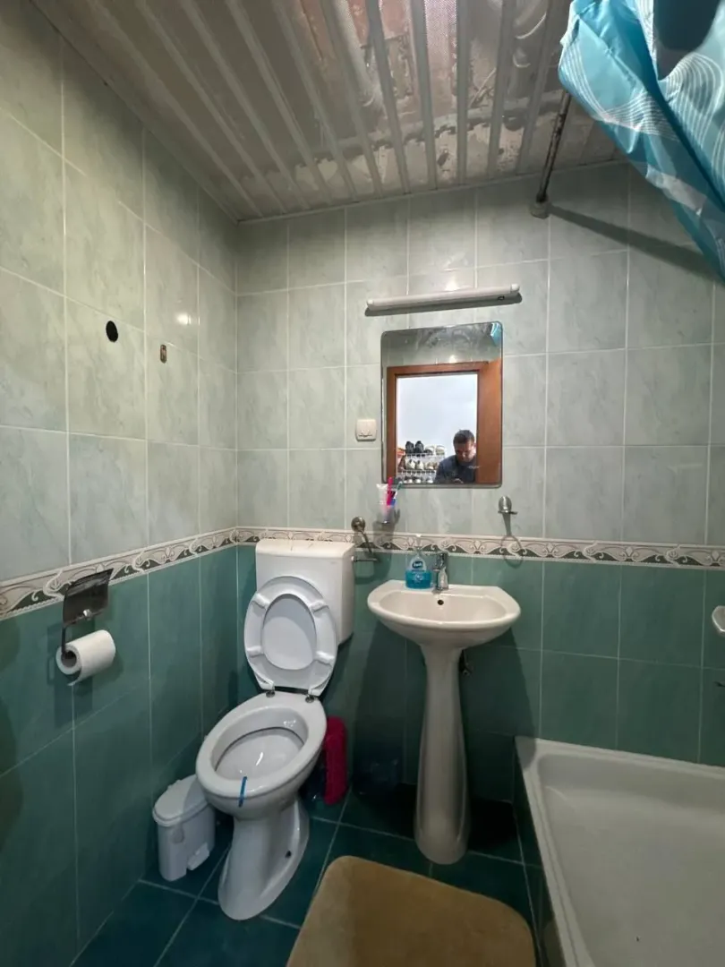 Manje kupatilo obloženo pločicama sa umivaonikom, WC šoljom i kadom.