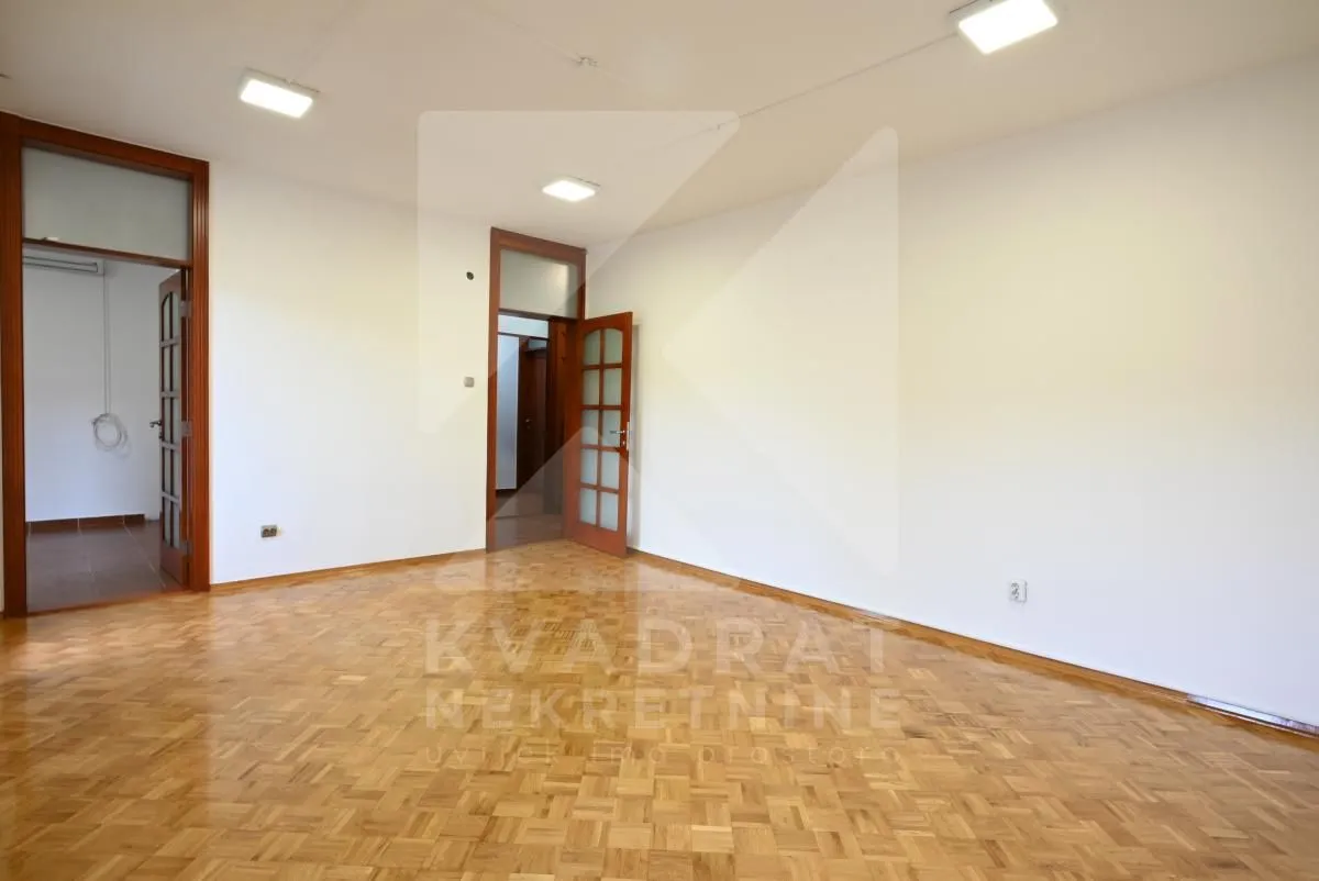 Empty room with parquet flooring and wooden doors.