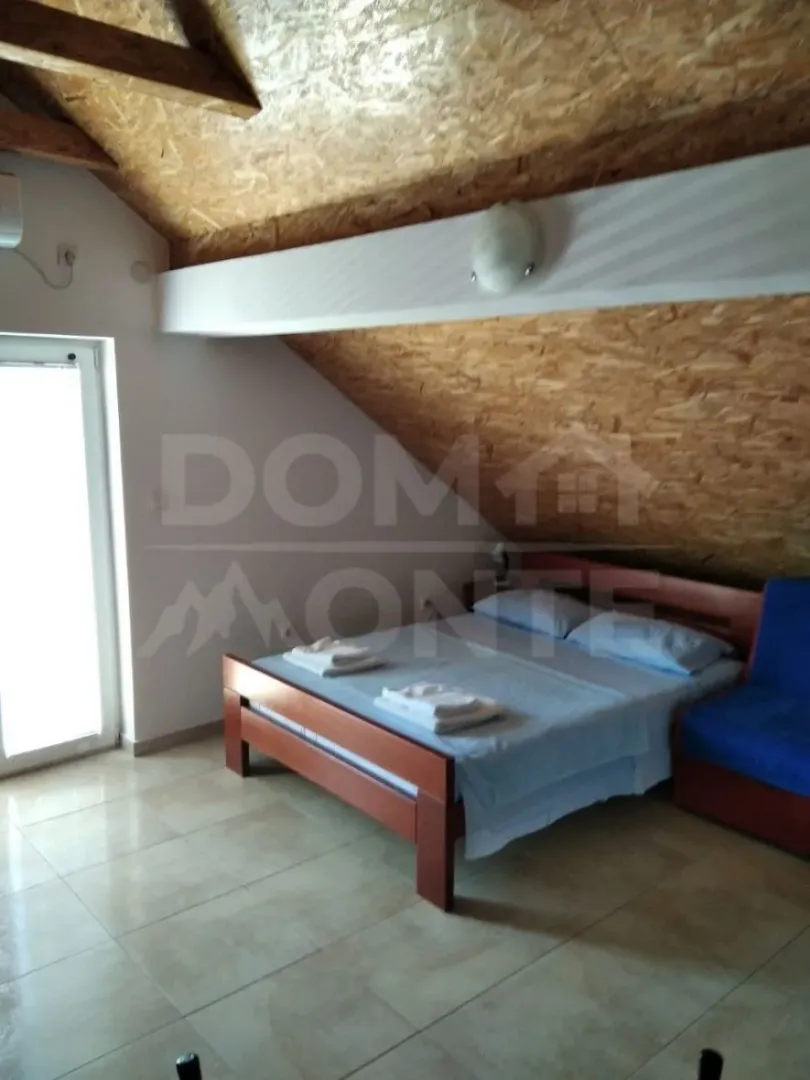 Attic bedroom with a double bed and a sloping OSB board ceiling.