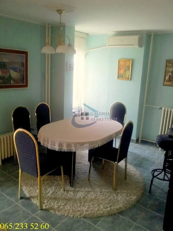 Trpezarija sa stolom, stolicama i tepihom na podu.