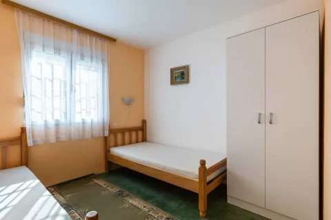 Manja spavaća soba sa drvenim krevetom, ormarom i prozorom. - image 30