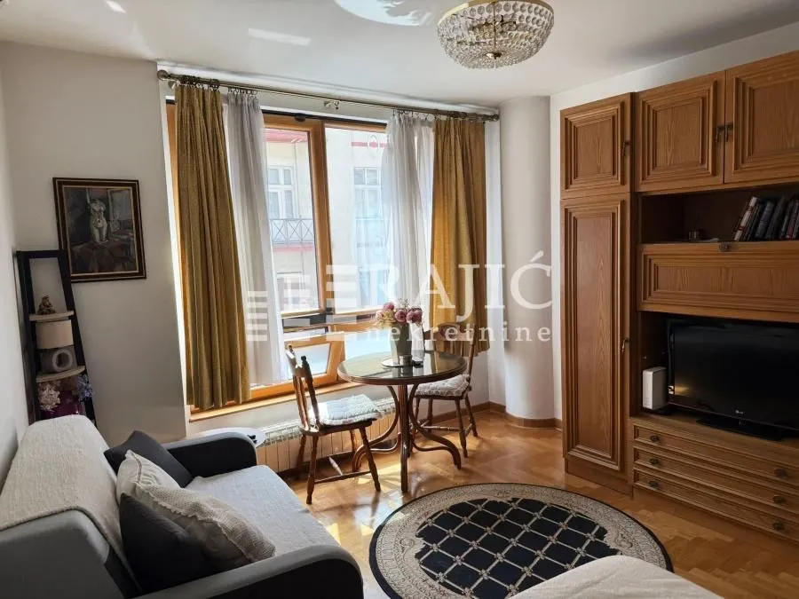 Living room with a sofa, dining table, and wooden closets.