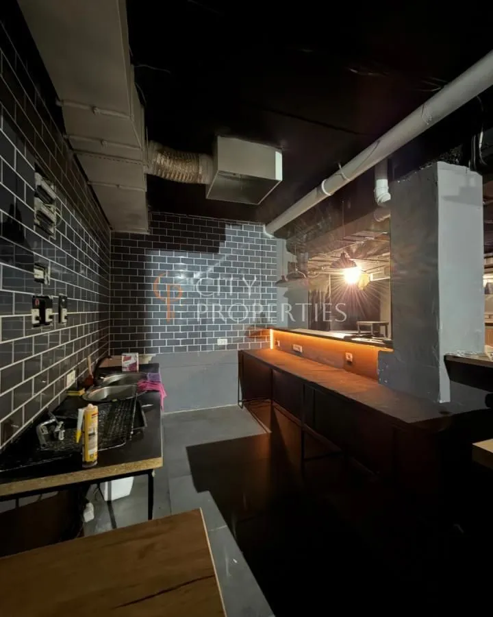 Kitchen space with dark ceramic tiles and a counter under furnishing.