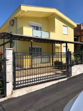 Exterior of a yellow facade house with a yard gate and fence. - image 2
