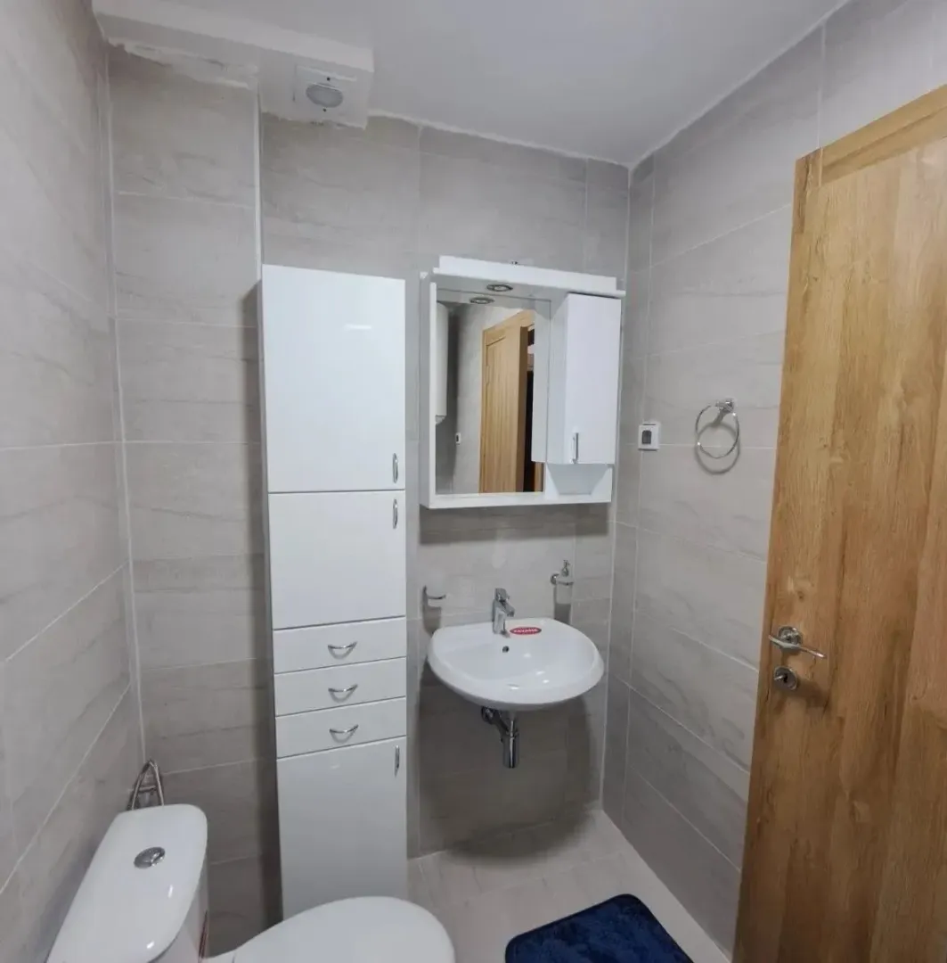 Manje kupatilo sa bijelim elementima, umivaonikom i wc šoljom.