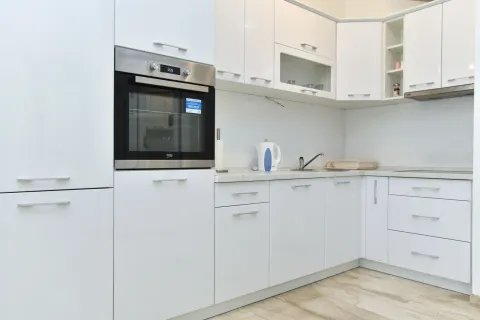 Modern white kitchen with a built-in oven and cabinetry. - image 9