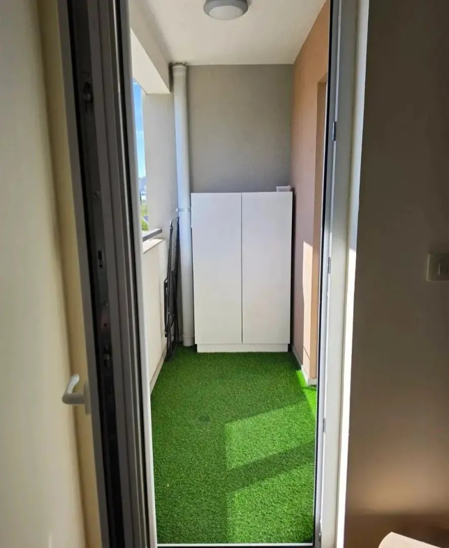 Pogled sa vrata na manju terasu sa vještačkom travom i ugradnim ormarićem.