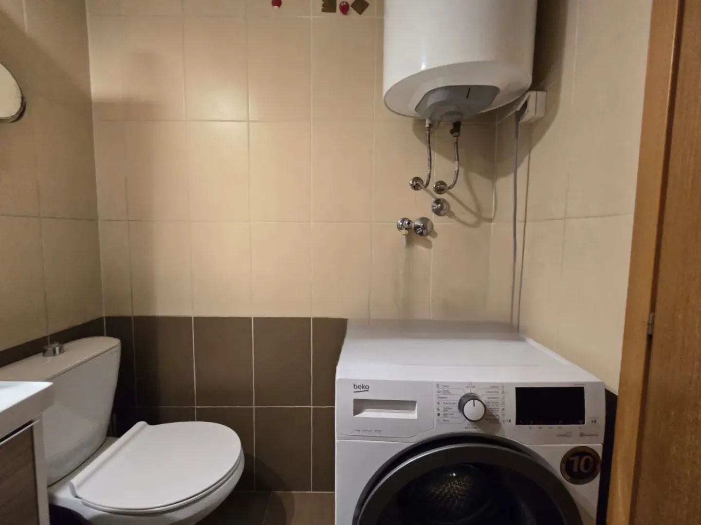Smaller bathroom with a toilet, washing machine, and water heater.