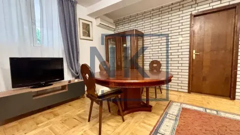 Living room with a wooden dining table, chairs, and a television. - image 5