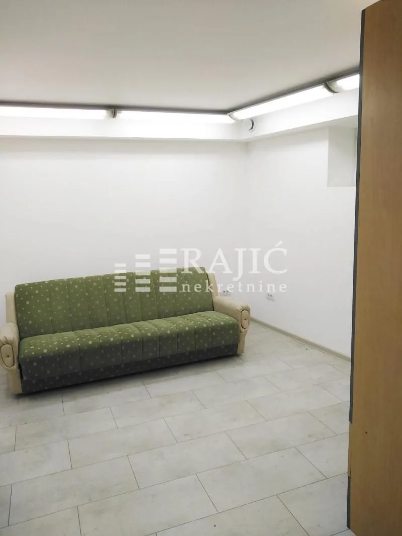 Living room with a green sofa and light tile flooring.
