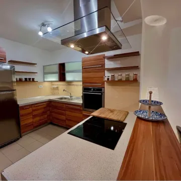 Modern kitchen with wooden cabinetry, island, and built-in appliances. - image 3