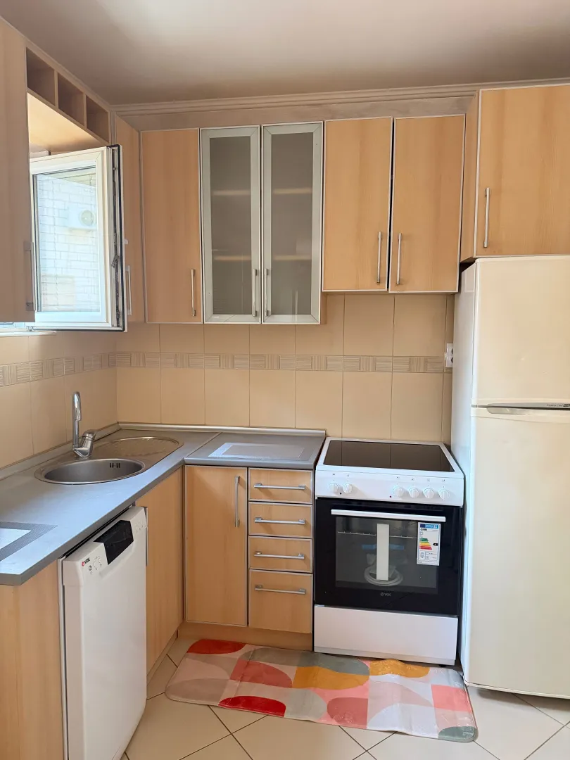 Small kitchen with wooden cabinets, stove, refrigerator, and sink.