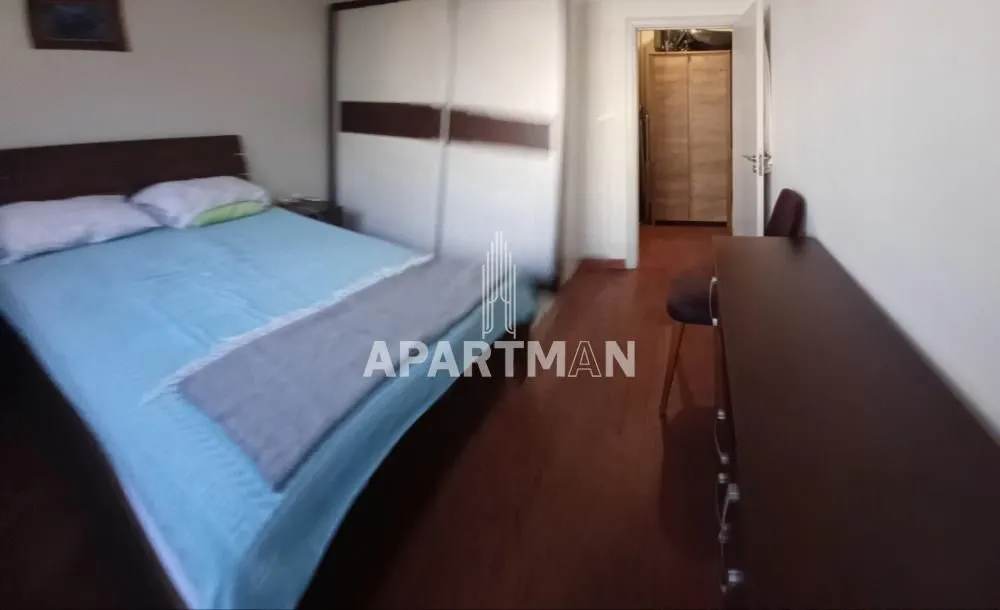 Nameštena spavaća soba sa bračnim krevetom, velikim garderoberom i komodom.