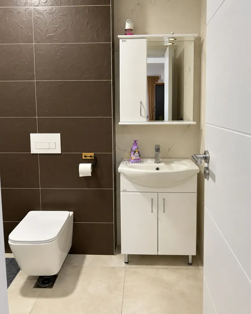 Moderne kupatilo sa bijelim umivaonikom, visećim elementom sa ogledalom i WC šoljom.