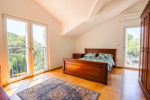 Prostrana spavaća soba sa bračnim krevetom, drvenim namještajem i izlazom na balkon. - image 10
