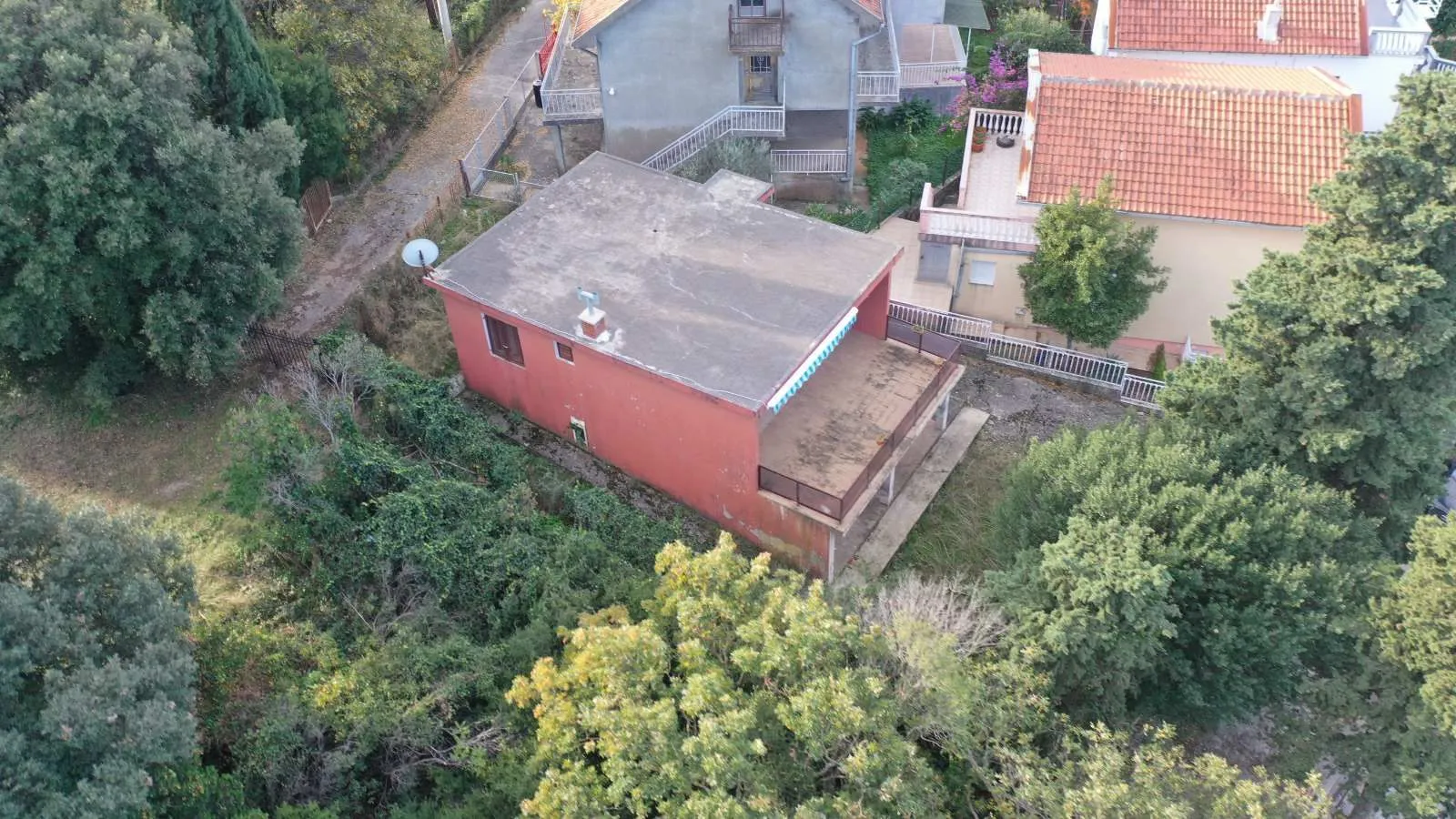 Pogled iz vazduha na porodičnu kuću sa terasom u zelenom okruženju.