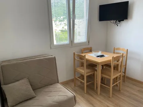 Living room with a sofa, dining table, and wall-mounted TV. - image 3