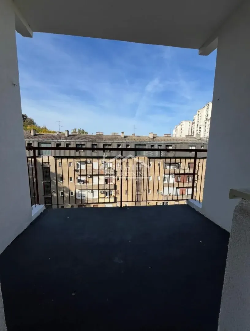 Nenamešten balkon sa pogledom na okolne zgrade.