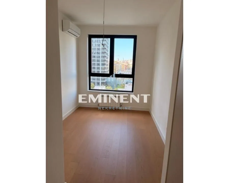Empty room with parquet flooring and an air conditioning unit.