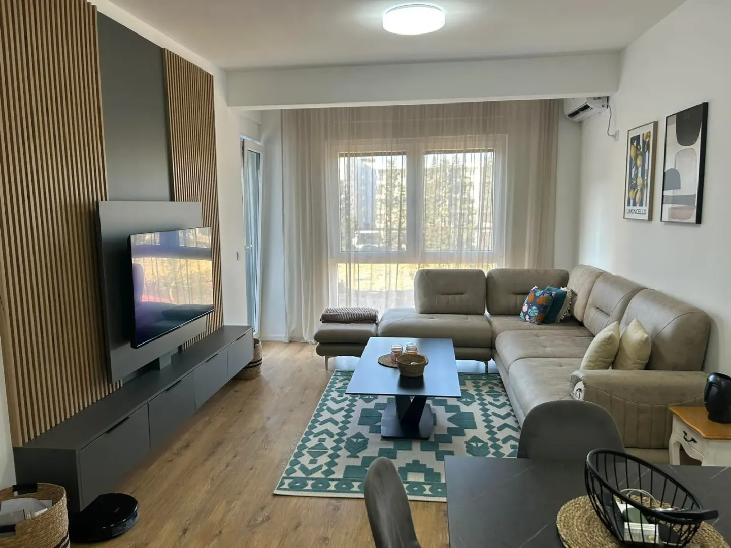 Modern living room with a sectional sofa, TV, and dining table in the foreground.